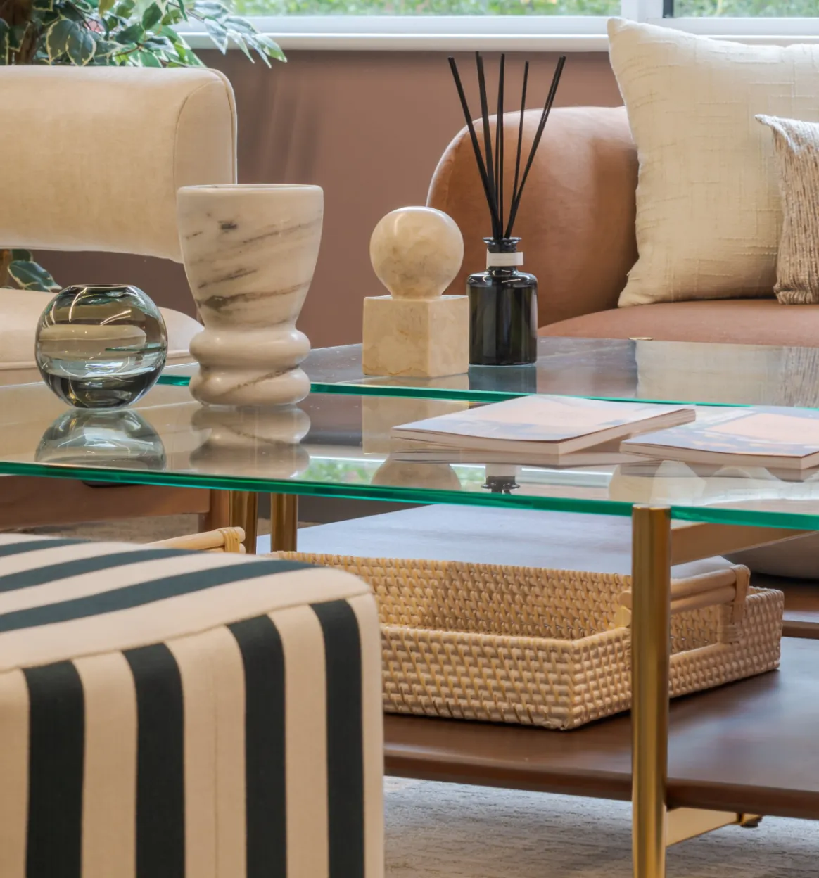 Marble vases, a reed diffuser and books on a glass coffee table